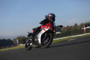 Motocicleta deportiva roja QJMOTOR tomando una curva en pista
